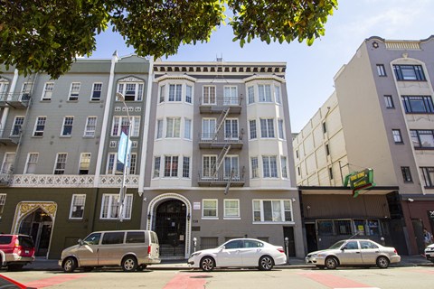 A street view of a building with cars parked in front.