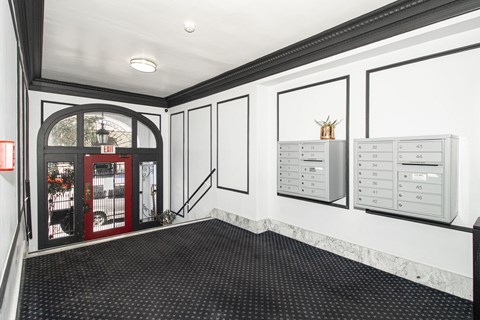 A hallway with a red door and a white wall with a calendar on it.