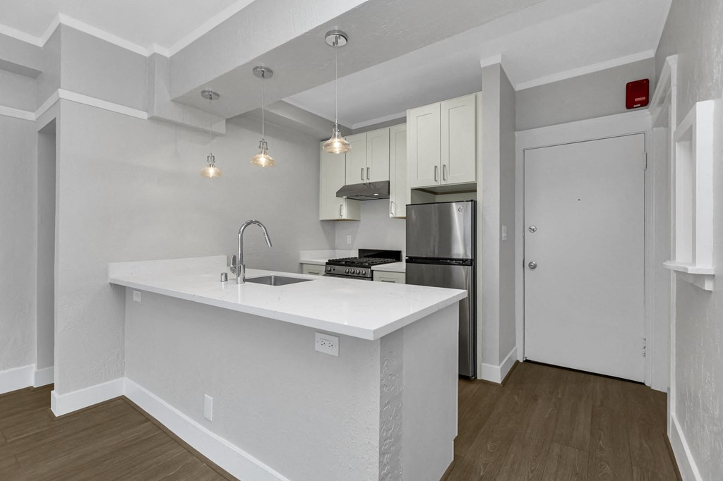 A kitchen with white cabinets and a white countertop.