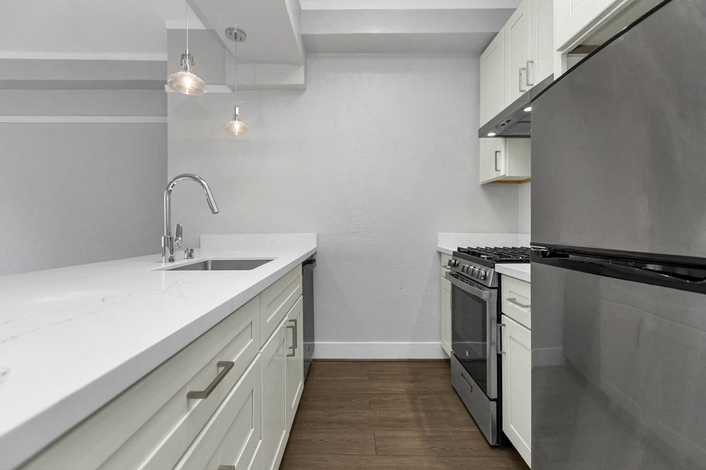 A modern kitchen with a stainless steel refrigerator and white countertops.