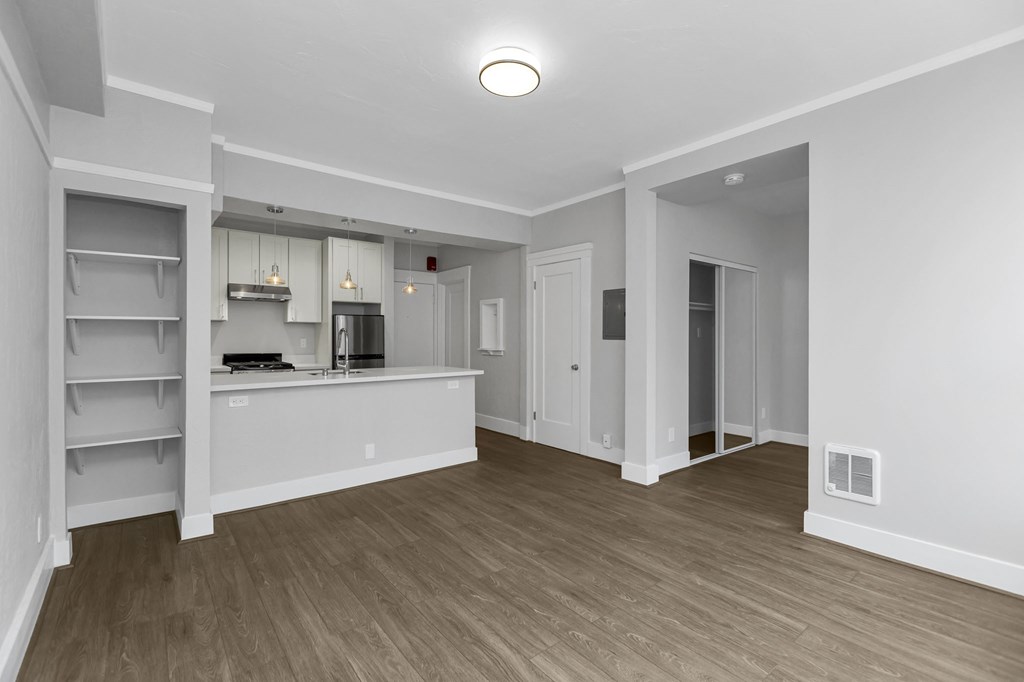 A kitchen area with a refrigerator, cabinets, and a countertop.