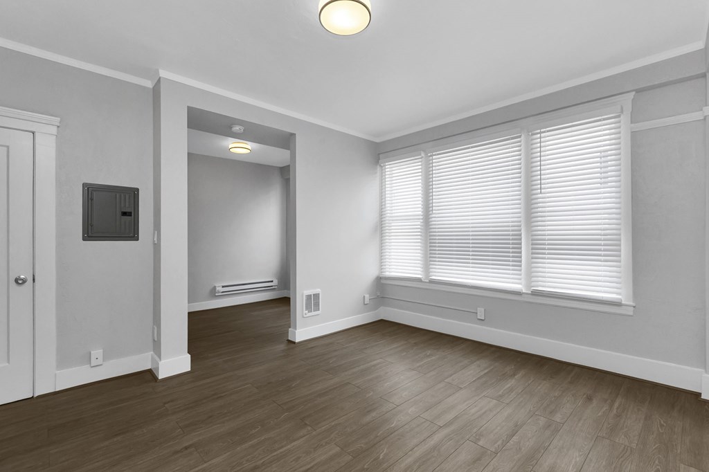 A room with a wooden floor and a window with blinds.