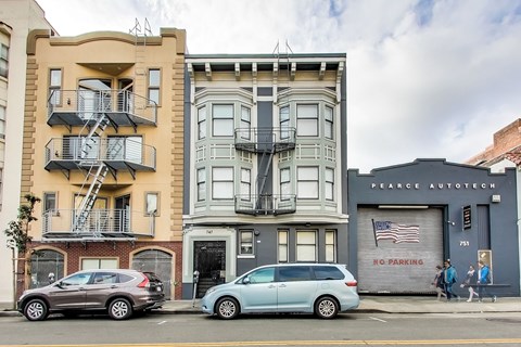 Two cars parked in front of a building with a no parking sign.