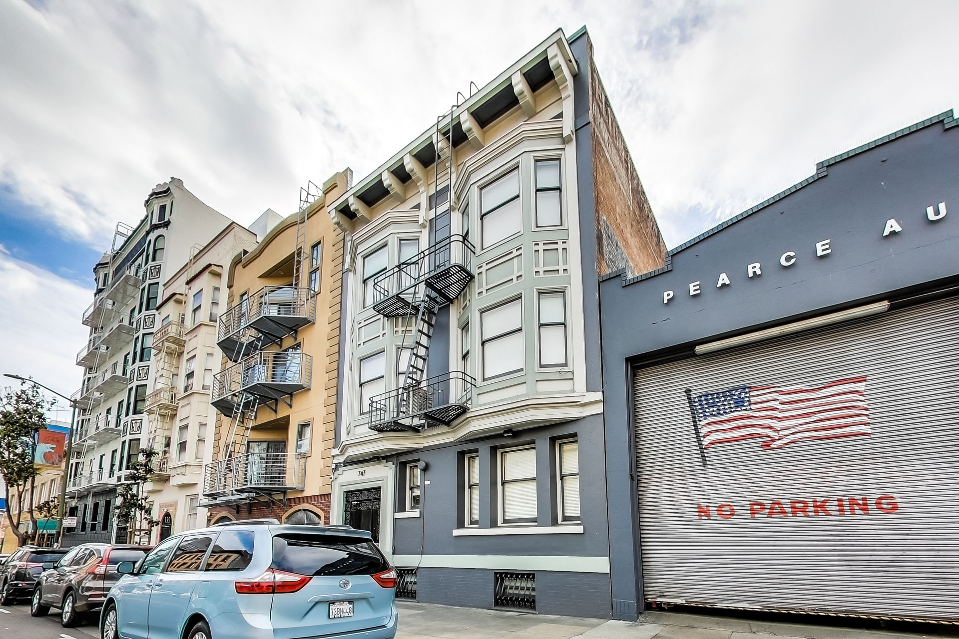 A street view with a car parked in front of a building with a no parking sign.