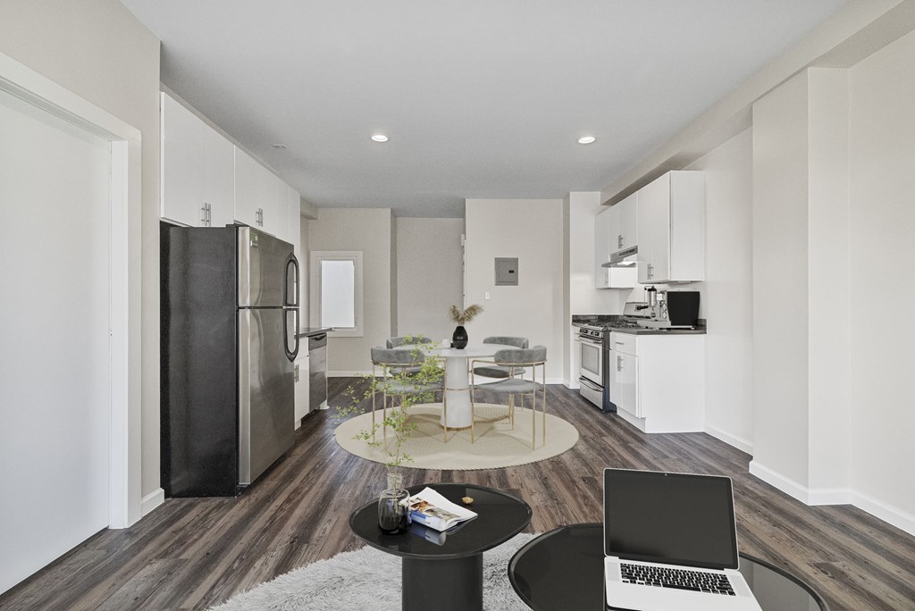 A modern kitchen with a black fridge and a laptop on the table.