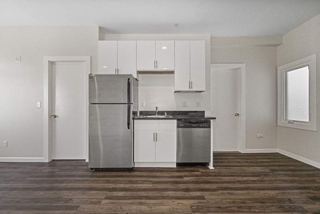 A kitchen with a refrigerator, cabinets, and a dishwasher.