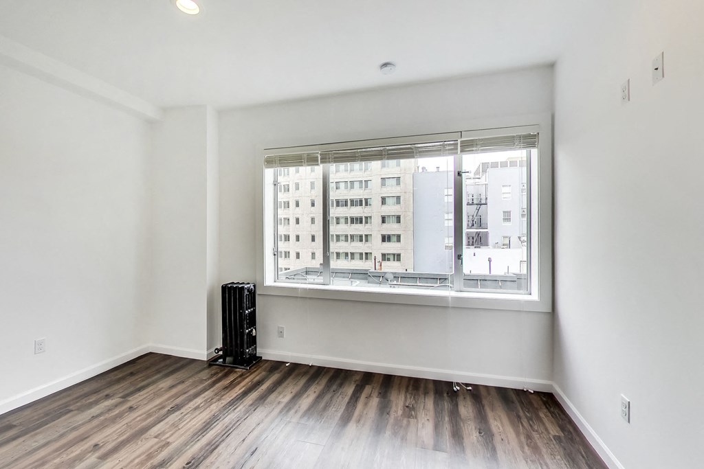an empty living room with a large window and wood flooring