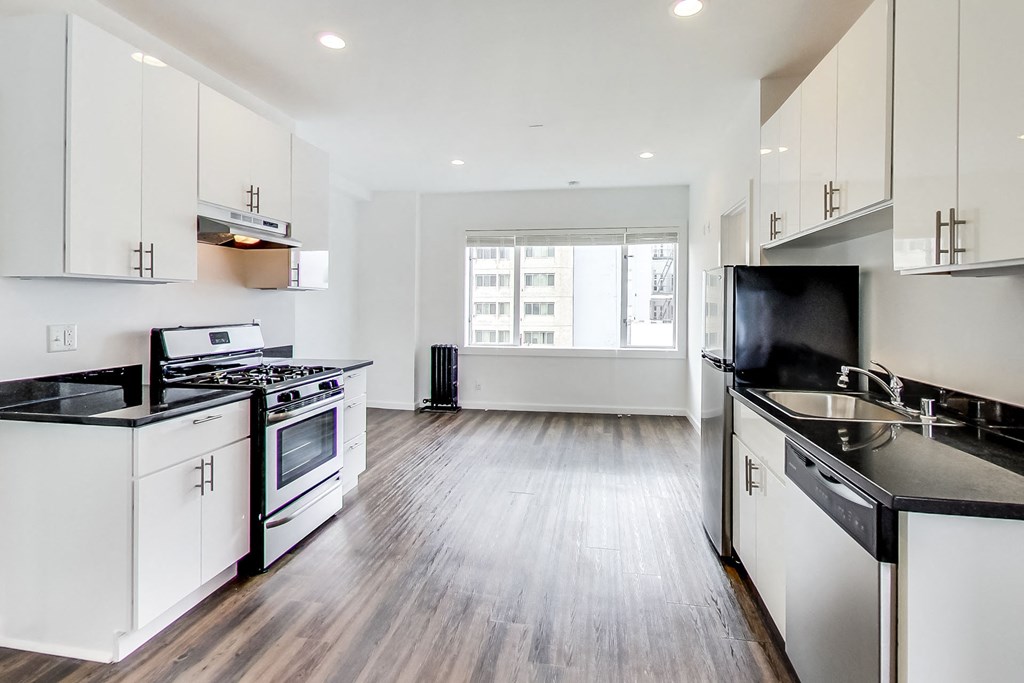 an empty kitchen with white cabinets and black counter tops