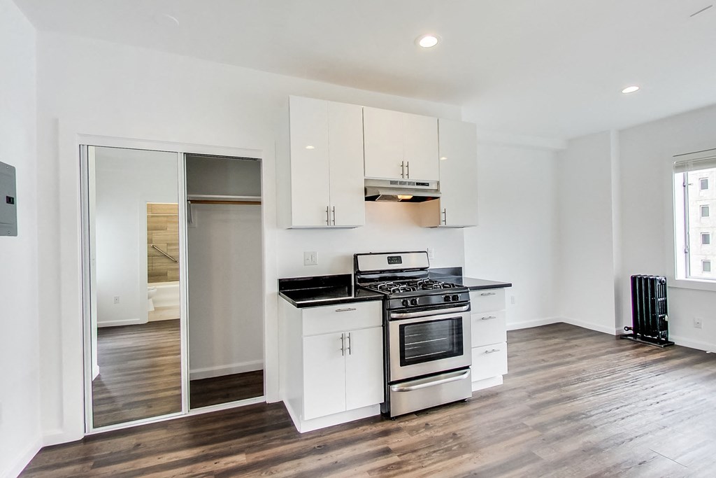 a kitchen with white cabinets and a stove and a window