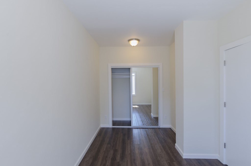 A hallway with a wooden floor and white walls.