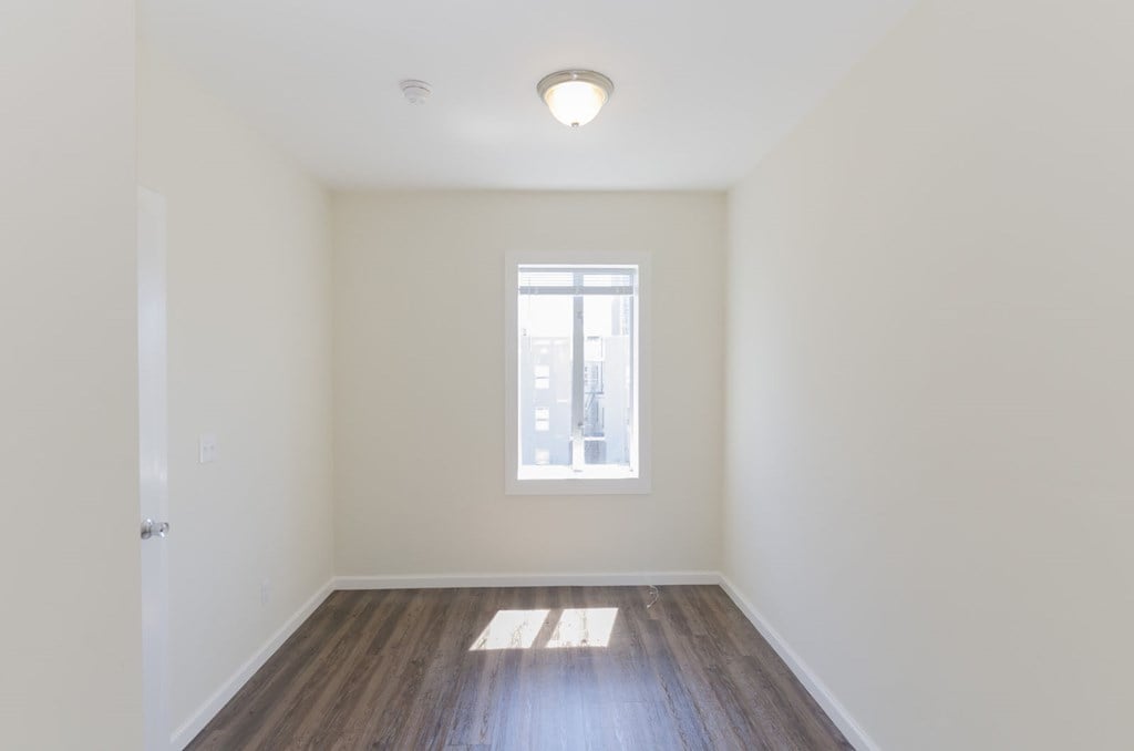 A room with a window and wooden floors.