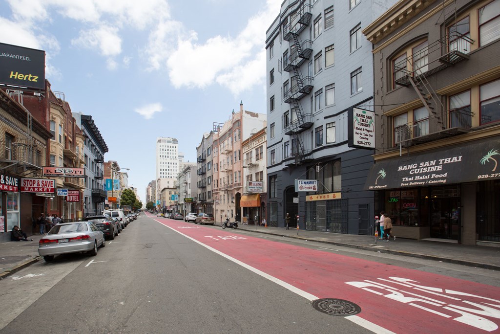 A street with a red bike lane and a sign that says "Hertz" on the side of a building.