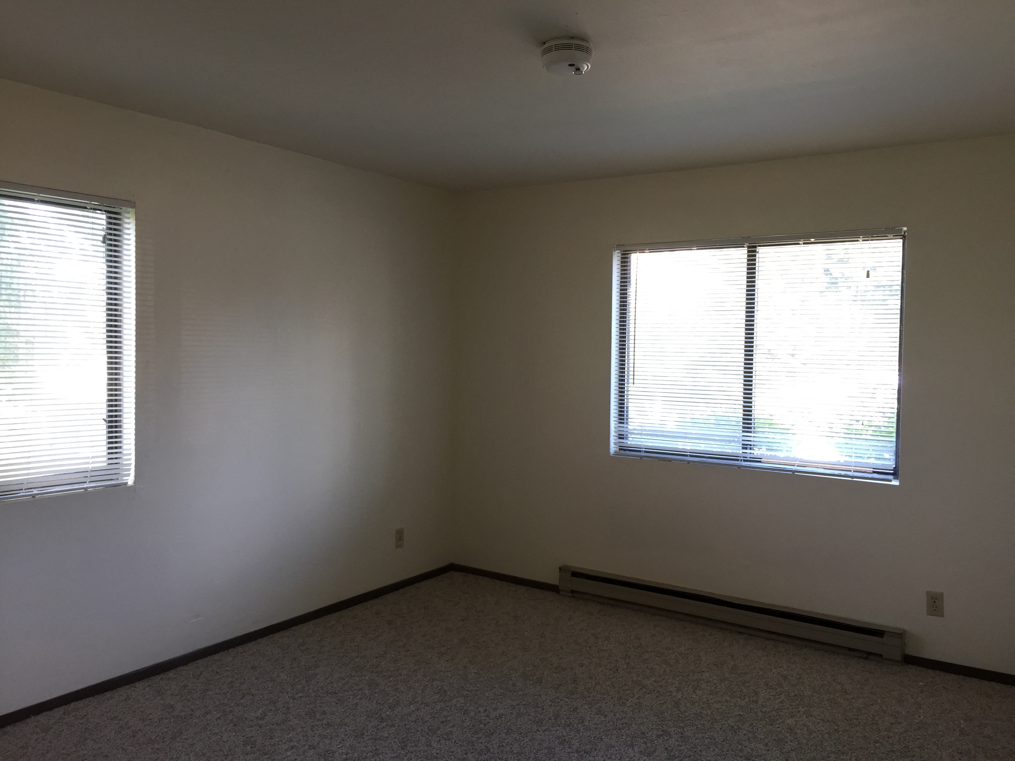 an empty room with two windows and white walls
