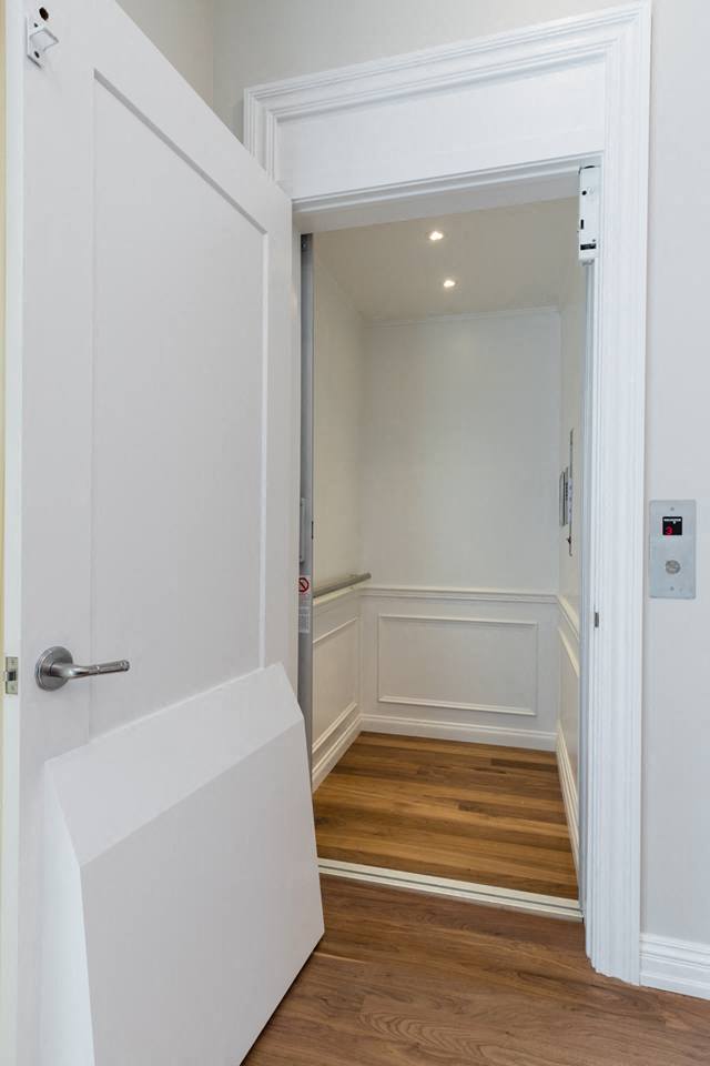 a small hallway with a white door and a wooden floor