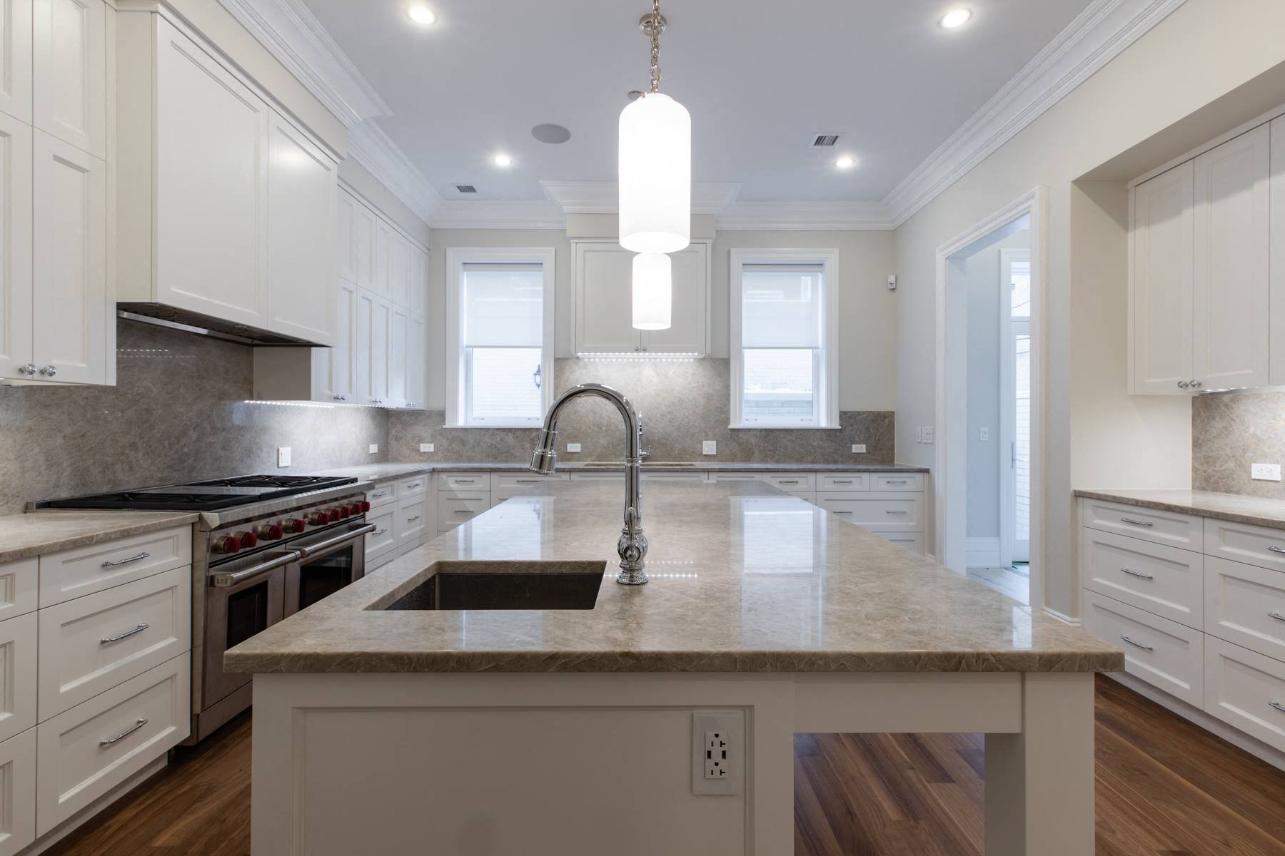 a large kitchen with white cabinets and a marble counter top
