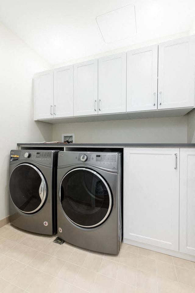 a washer and dryer in a laundry room with white cabinets