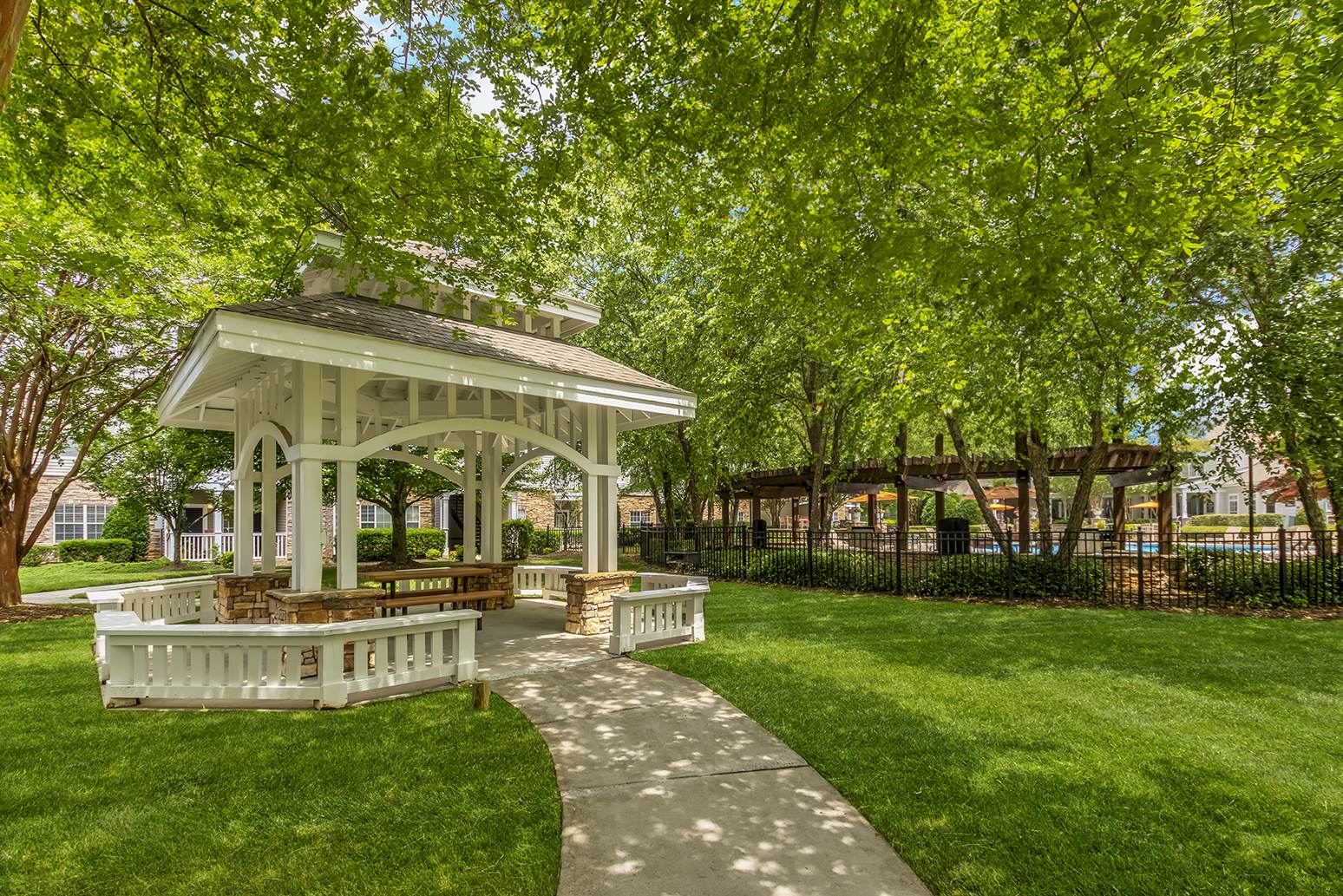 a white gazebo in the middle of a park with benches