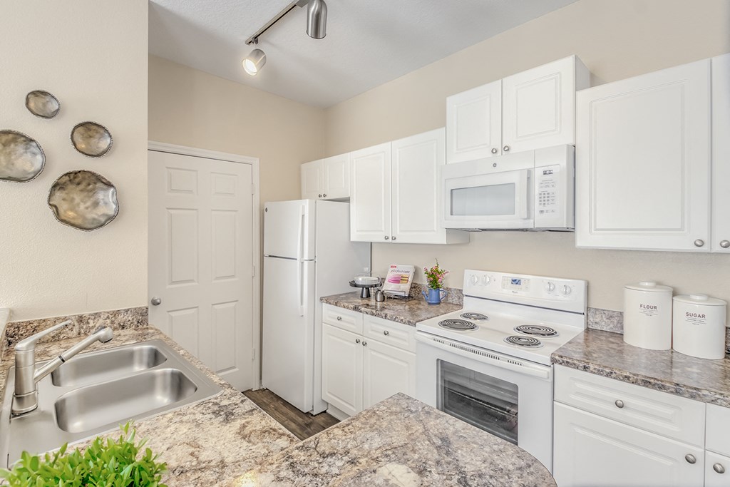 a kitchen with white appliances and granite counter tops