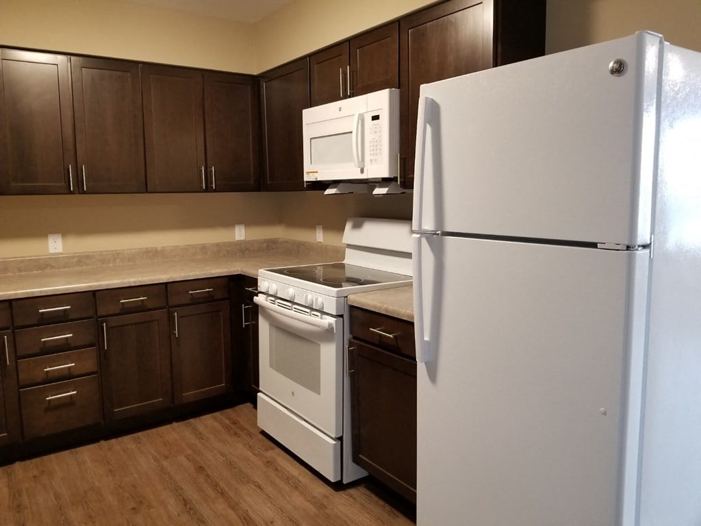 a kitchen with white appliances and dark wood cabinets