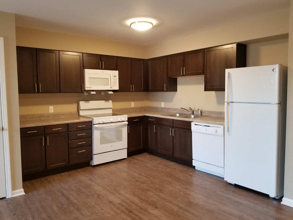 an empty kitchen with white appliances and brown cabinets