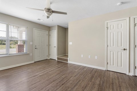 an empty living room with a ceiling fan and a window