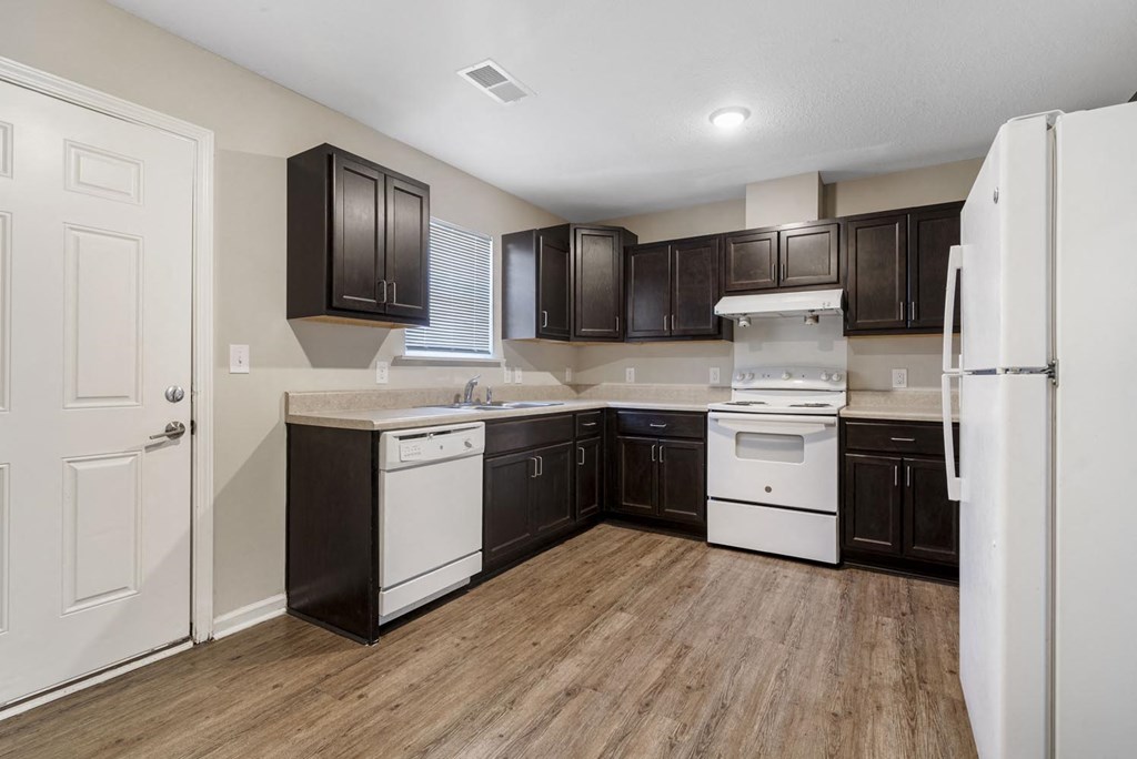 a kitchen with dark wood cabinets and white appliances