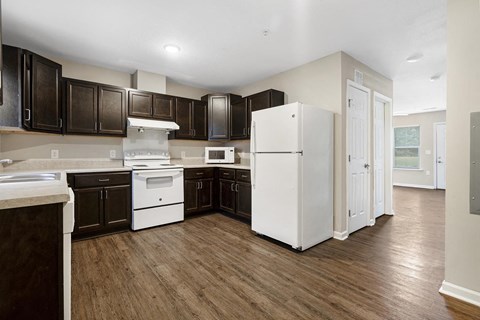 a large kitchen with white appliances and dark cabinets