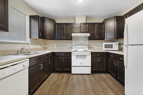 a kitchen with dark wood cabinets and white appliances