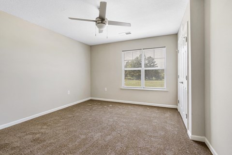 an empty room with a ceiling fan and a window
