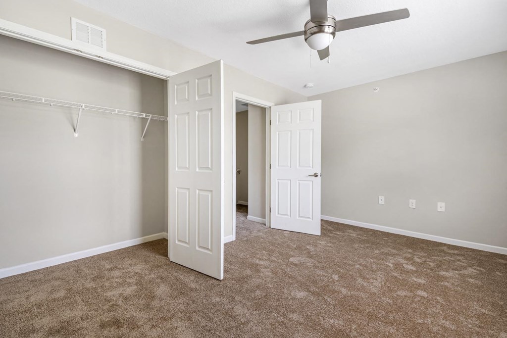 an empty living room with a ceiling fan and a closet
