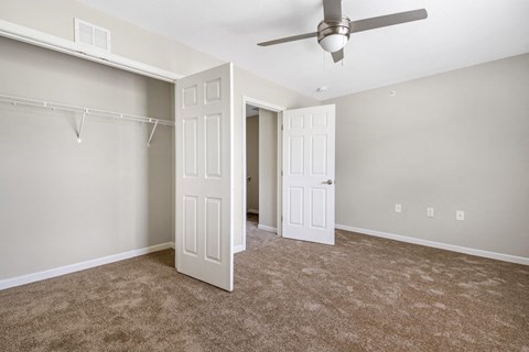 an empty living room with a ceiling fan and a closet