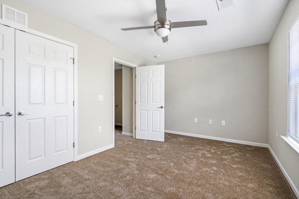 a bedroom with two doors and a ceiling fan