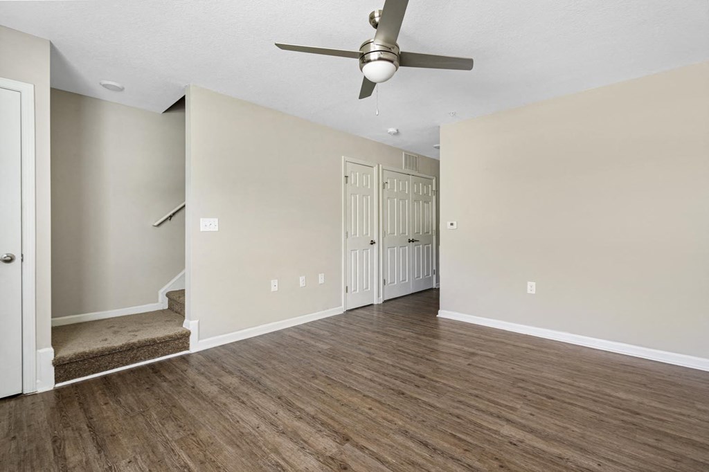 an empty living room with a ceiling fan