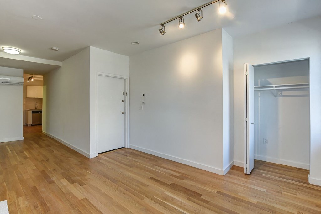 a living room with a door to a closet and a hard wood floor