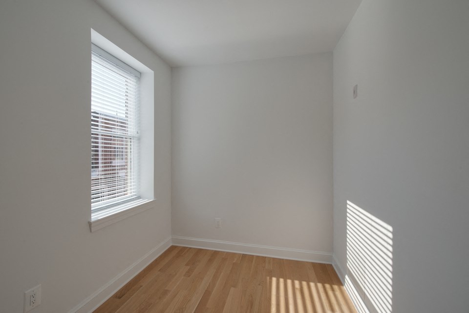 a bedroom with a large window and wood flooring