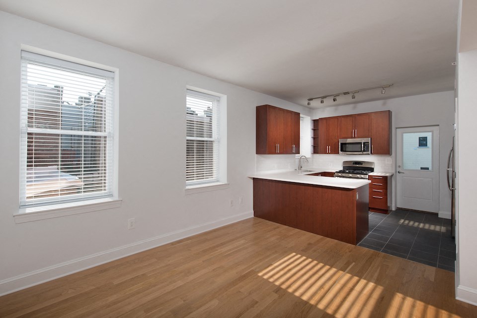 an empty kitchen with wood flooring and a large window