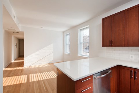 an empty kitchen with white counter top and wooden cabinets