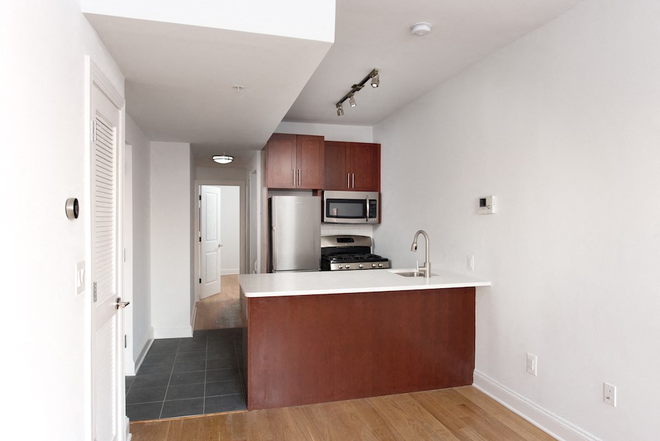 a kitchen with a white counter top and a stainless steel refrigerator
