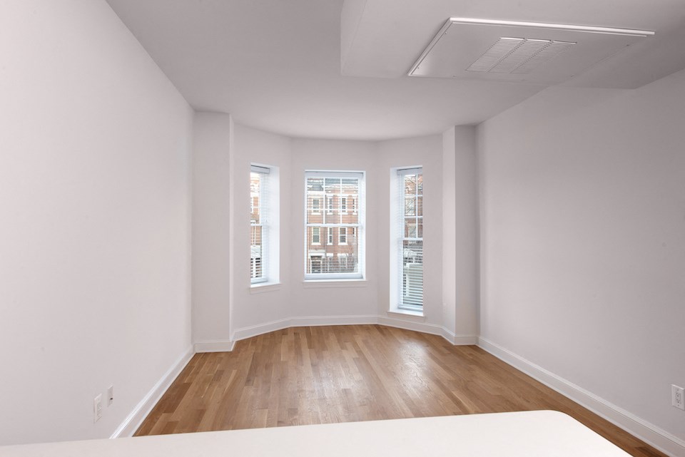 an empty room with white walls and wooden floors and three windows