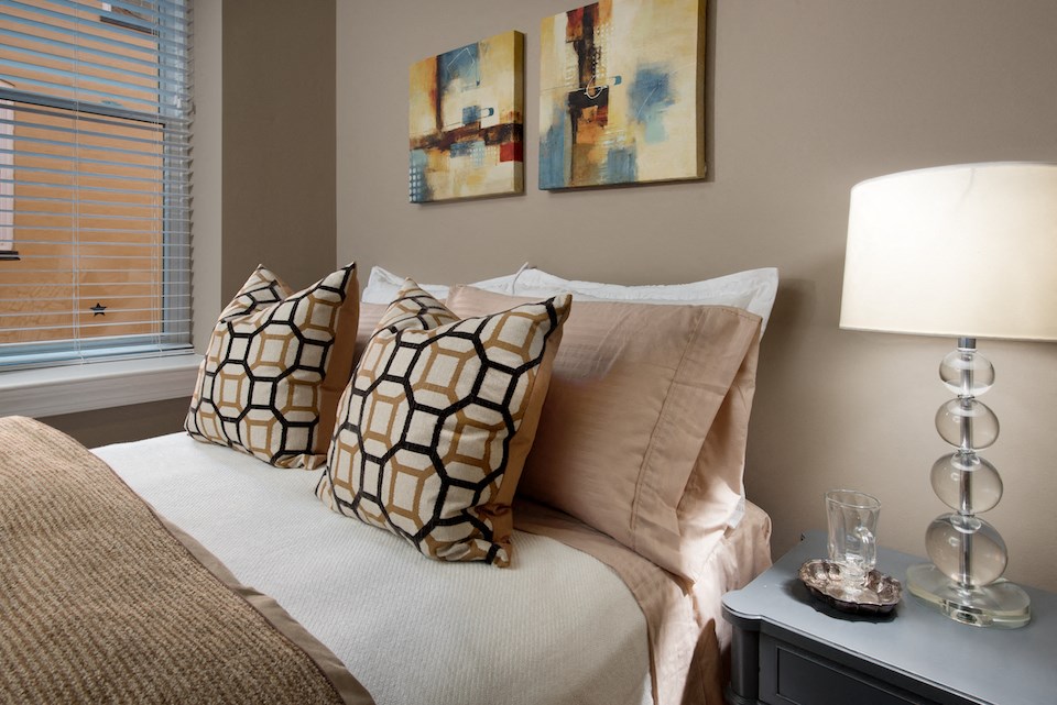 a bedroom with a bed with pillows and paintings on the wall