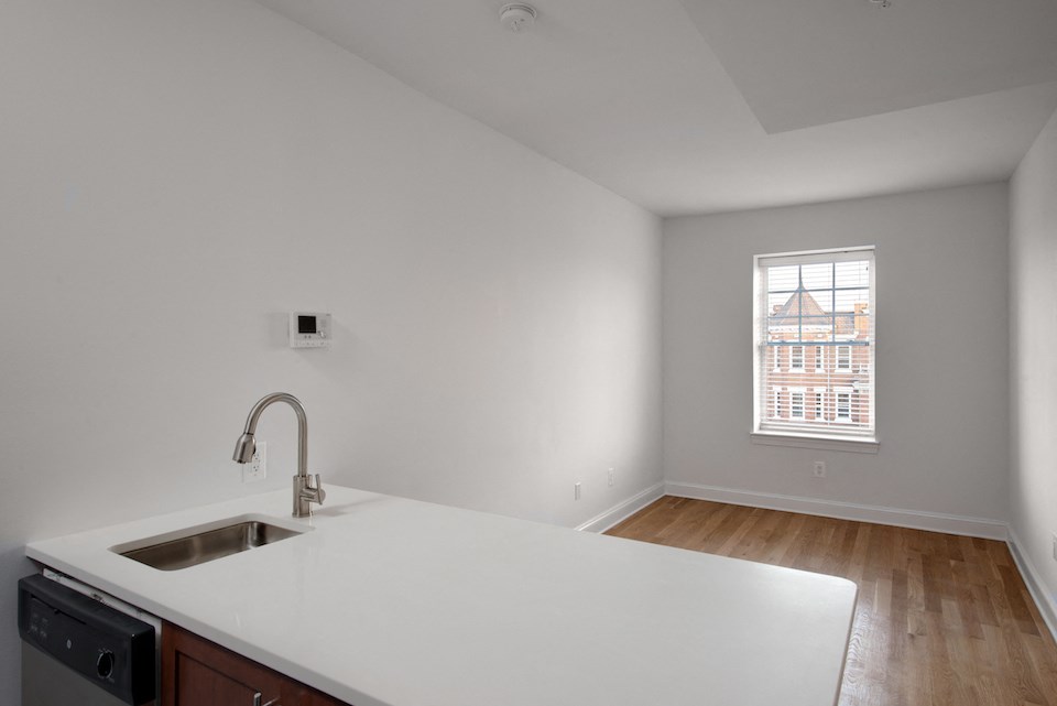 an empty kitchen with white countertops and a sink and a window
