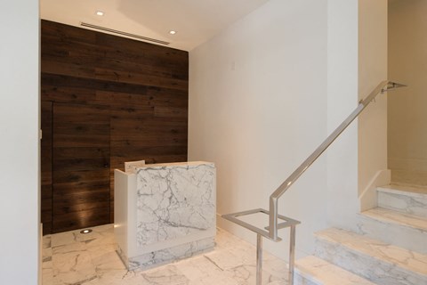 a marble staircase with a wooden wall and a marble reception desk in a lobby