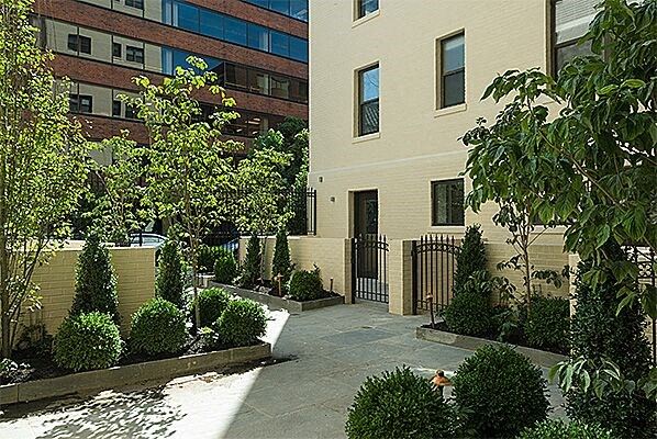 a courtyard with trees and bushes in front of a building