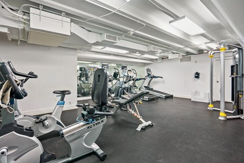 A gym with a row of treadmills and elliptical machines.