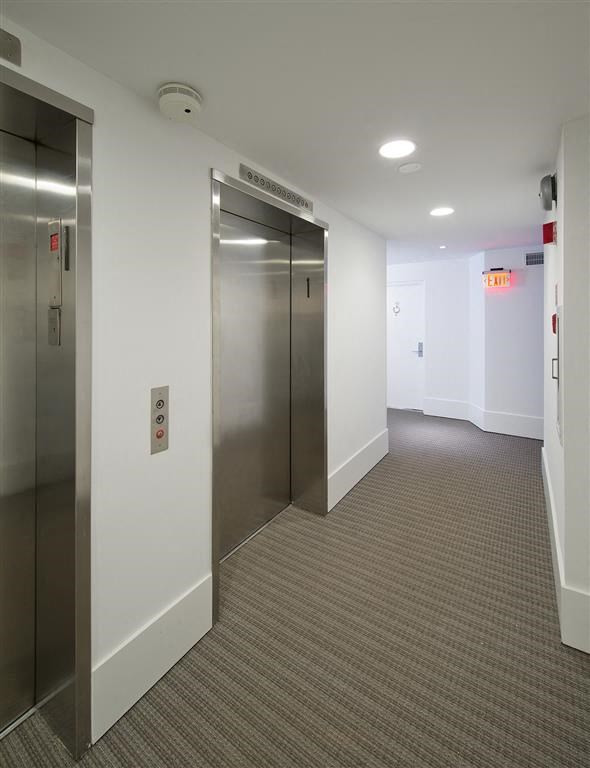 a hallway with stainless steel elevators in a building