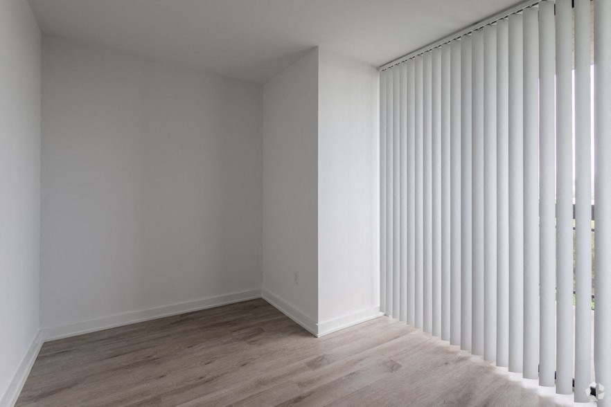 a living room with white blinds on the wall and wooden floors