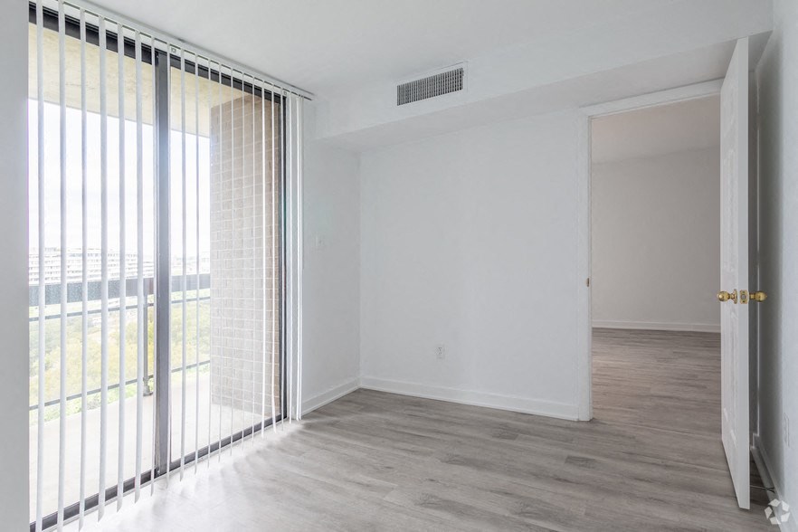 an empty living room with a sliding glass door to a balcony