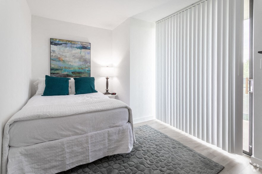 a bedroom with a bed and a window with white blinds