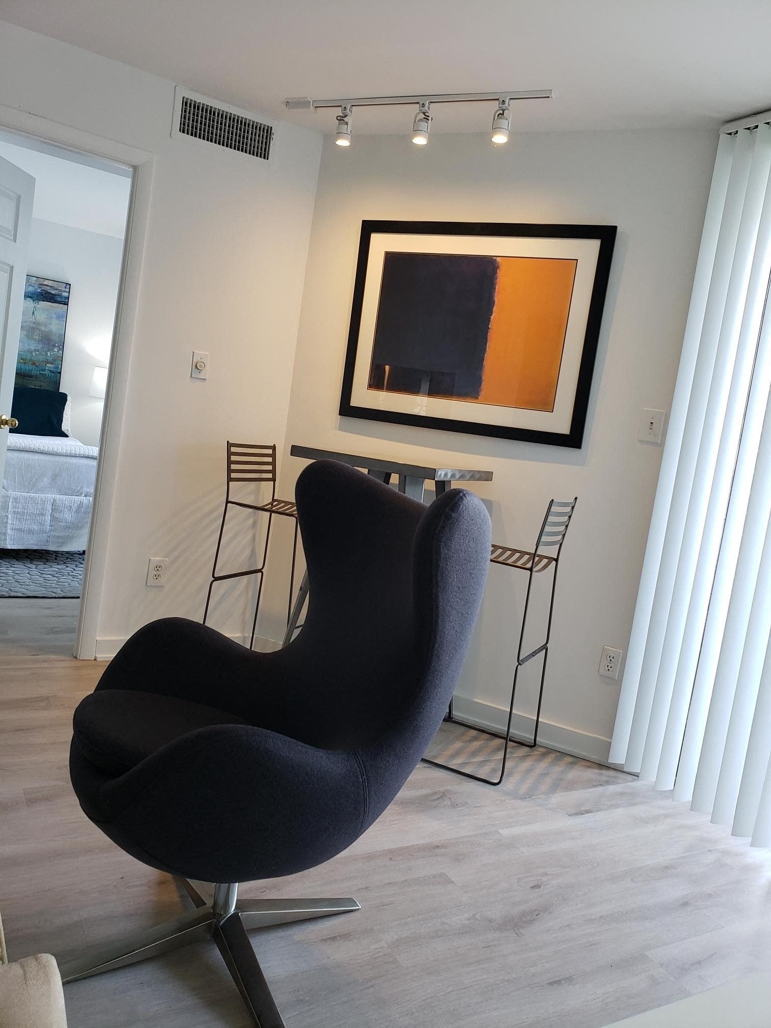 a black chair in a room with a desk and a painting on the wall