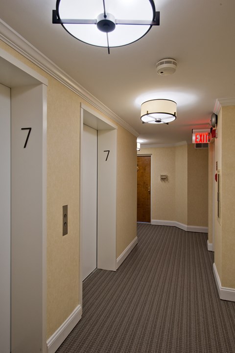 a hallway with doors and a ceiling light and a exit sign